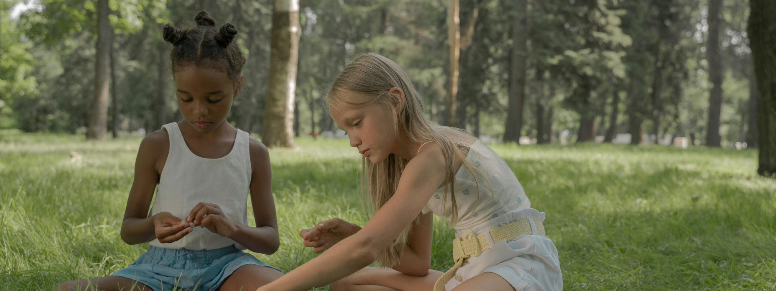 Two girls outdoors, making something with their hands